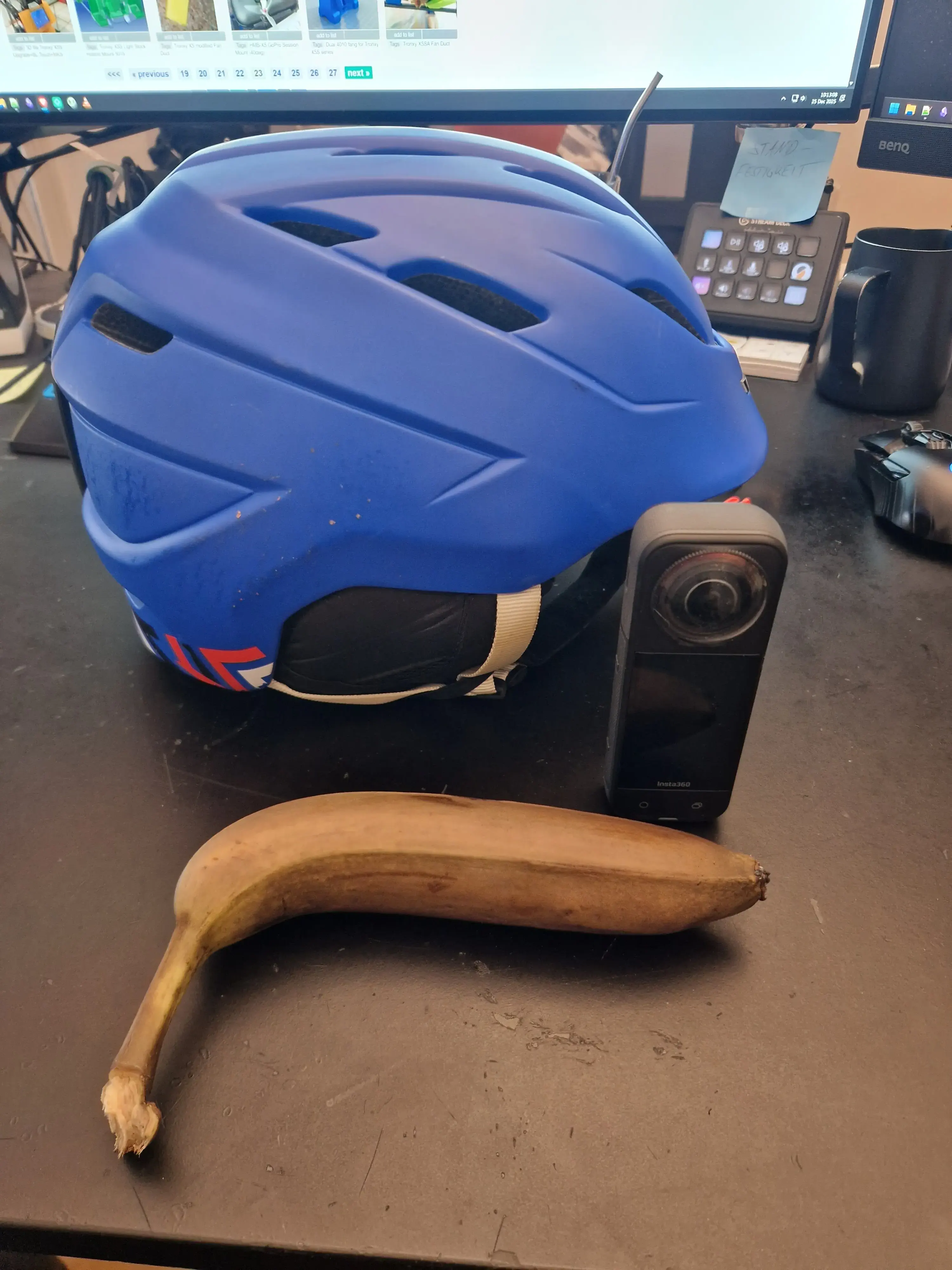 Helm, Kamera und eine Banane nebeneinander auf dem Schreibtisch